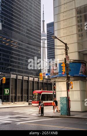 TORONTO, KANADA - 06 05 2021: Fußgänger und Straßenbahn vor dem Toronto Dominion Bank Tower in der King at Bay Street mit CN Tower sichtbar dazwischen Stockfoto