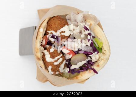 Blick von oben auf das Pita Wrap Sandwich mit Fleisch, mundgroßen Falafels und Gemüsefüllungen für eine köstliche mediterrane Mahlzeit. Stockfoto