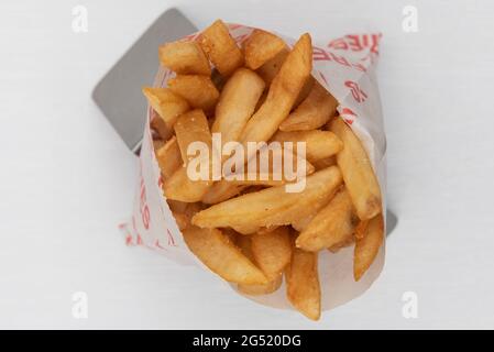 Ansicht von oben über die Seitenreihenfolge einer Tüte knuspriger pommes, die in einer Tüte serviert und für eine großartige Vorspeise aufrecht präsentiert werden. Stockfoto