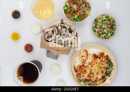 Riesige Auswahl an mediterranen Gerichten auf einem weißen Tisch mit dem Pita Wrap Sandwich in der Mitte des Essens. Stockfoto