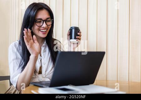 Glückliche Geschäftsweiblich winkende Hand reden Online-Videoanruf verwenden Laptop sitzen am Tisch im Café Stockfoto