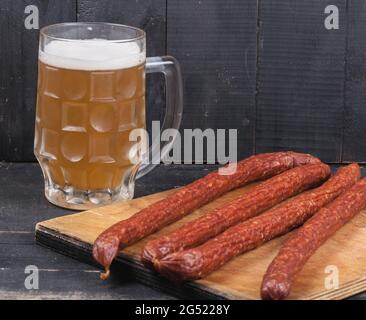 Lange Fleischwürste mit einem Glas Bier auf Holzhintergrund aus nächster Nähe Stockfoto