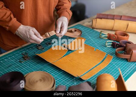 Prozess Schneidschema von Beutel mit Geräten und Materialien. Männlicher Gerber, der in der Lederwerkstatt arbeitet Stockfoto