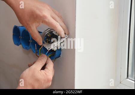 Steckdose, Steckdose, Netzstecker. Während der Renovierung wird ein Elektriker installiert, der die Kabel an eine neue Steckdose anführt. Stockfoto