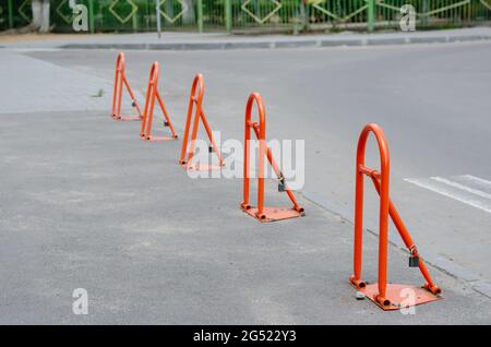 Parkbarrieren in einer Reihe. Fünf orangefarbene Metall-Klappbarrieren auf dem Bürgersteig. Tagsüber. Stockfoto