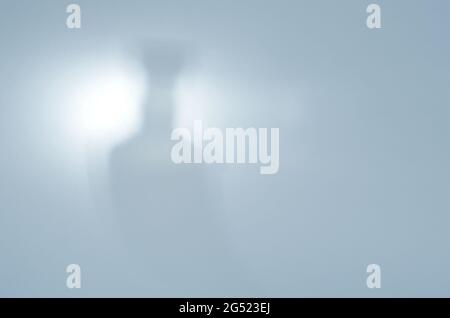 Flasche im Licht. Verschwommene Silhouette einer Whiskey-Flasche auf Blau. Unschärfter Schatten mit Rauschen. Abstrakter Hintergrund. Stockfoto