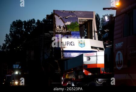 Bad Zwischenahn, Deutschland. Juni 2021. Auf einer Straße steht in der Dämmerung ein Tieflader, beladen mit dem ersten Teil des in der Längsrichtung halbgesägten Passagierschiffs MS Oldenburg. Nach zwei Stunden kam die erste Hälfte des ehemaligen Ausflugsdampfers in der Nacht auf einem Tieflader in Oldenburg an. (To dpa 'Sondertransport mit halbem Ex-Dampfer in Oldenburg angekommen') Quelle: Hauke-Christian Dittrich/dpa/Alamy Live News Stockfoto