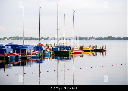 Bad Zwischenahn, Deutschland. Juni 2021. Segelboote liegen in der Abendsonne auf einem Steg im ruhigen Wasser des Zwischenahner Meeres. Quelle: Hauke-Christian Dittrich/dpa/Alamy Live News Stockfoto