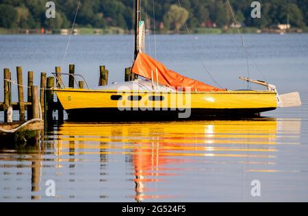 Bad Zwischenahn, Deutschland. Juni 2021. Ein gelbes Segelboot liegt in der Abendsonne auf einem Steg im ruhigen Wasser des Zwischenahner Meeres. Quelle: Hauke-Christian Dittrich/dpa/Alamy Live News Stockfoto