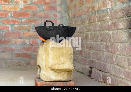 Traditioneller indischer Chulha aka Ofen in Flammen mit schwarzem Kessel und rotem Backsteinwand Hintergrund. Ein diy-Ofen oder Grill aus Schlamm und Zement in Schurken. Stockfoto