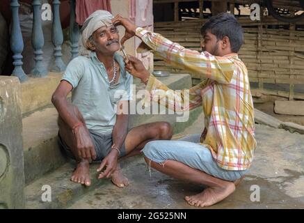 Erstaunliche Foto zeigt Vater Sohn Beziehung der Liebe und Fürsorge in der Familie. Der junge Sohn hilft seinem Vater mittleren Alters, indem er zu Hause einen Salondienst leistet. Stockfoto