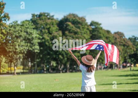 Frau, die mit der Flagge der Vereinigten Staaten von Amerika im Park im Freien reist. USA: Feiertag der Veteranen, Gedenkstätte, Unabhängigkeit (4. Juli) und Tag der Arbeit CO Stockfoto