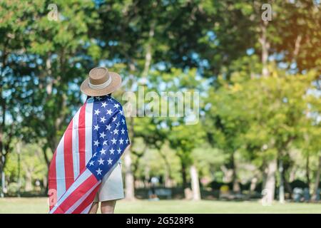 Frau, die mit der Flagge der Vereinigten Staaten von Amerika im Park im Freien reist. USA: Feiertag der Veteranen, Gedenkstätte, Unabhängigkeit (4. Juli) und Tag der Arbeit CO Stockfoto
