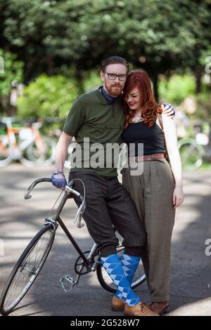 Junges Paar in Vintage-Kleidung, das neben dem Fahrrad beim Tweed Run in London, Großbritannien, steht Stockfoto