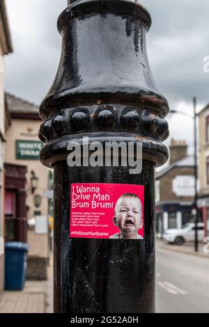 Ein roter Anti-Auto-Aufkleber überführt die Fahrer auf einem Lampenpfosten auf der Mill Road, Cambridge, zu einem weinenden Baby. Stockfoto