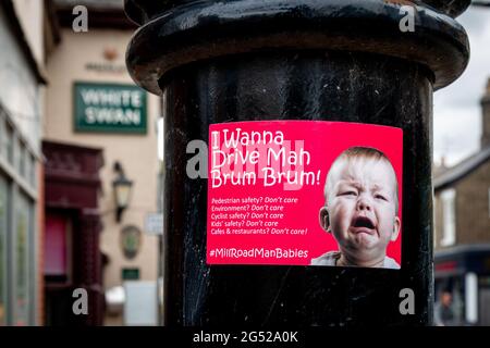 Ein roter Anti-Auto-Aufkleber überführt die Fahrer auf einem Lampenpfosten auf der Mill Road, Cambridge, zu einem weinenden Baby. Stockfoto