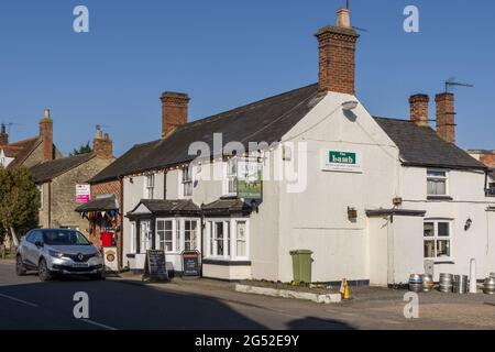 Straßenszene im Frühling im Dorf Stoke Goldington, Buckinghamshire, Großbritannien; Außenansicht des Lamb Pub. Stockfoto