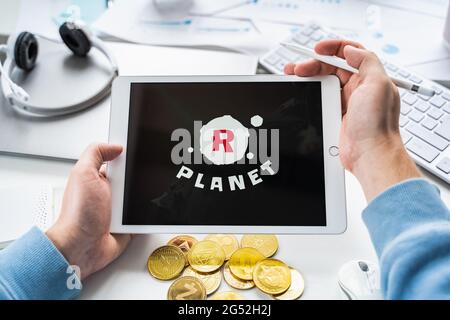 Russland Moskau 05.05.2021.man hält Tablet mit Logo der Gaming-Plattform R Planet. Krypto-Münzen, Token Bergbau Online-Spiel. NFT-Abstapelsystem. Krypto Stockfoto