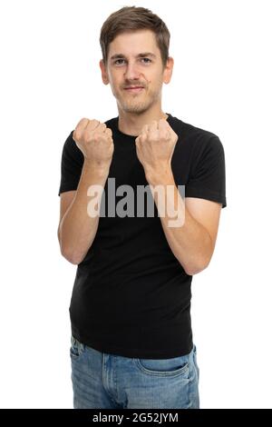 Junger, hübscher, großer, schlanker, weißer Mann mit braunem Haar, der sich in einem schwarzen Hemd in blauer Jeans auf weißem Hintergrund energiegeladen fühlt Stockfoto