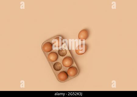 Natürliche Bio-Eier in Holzeikiste auf beigem Hintergrund. Kompositionen in monochromen Farben. Zero Waste Konzept. Stockfoto