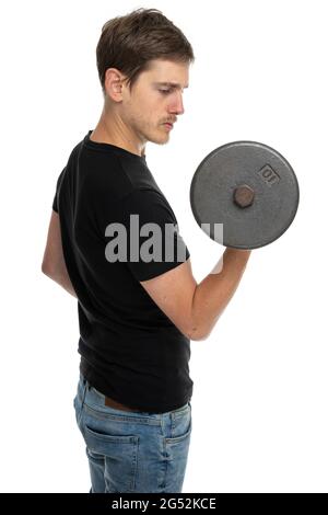Junger, hübscher, großer, schlanker weißer Mann mit brauner Hantel in schwarzem Hemd in blauer Jeans, isoliert auf weißem Hintergrund Stockfoto