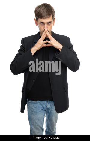 Junger, hübscher, großer, schlanker weißer Mann mit braunem Haar sieht in schwarzem Blazer in blauer Jeans auf weißem Hintergrund isoliert aus Stockfoto