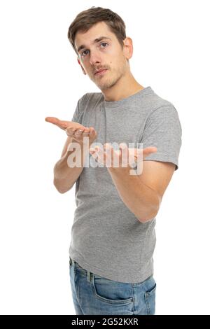 Junger, hübscher, großer, schlanker weißer Mann mit braunen Haaren lädt Sie in grauem Hemd in blauer Jeans ein, isoliert auf weißem Hintergrund Stockfoto
