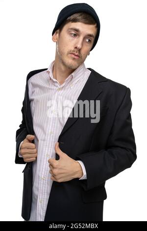 Junger, hübscher, großer, schlanker weißer Mann mit braunem Haar sieht traurig aus in schwarzem Blazer mit schwarzem Winterhut, isoliert auf weißem Hintergrund Stockfoto