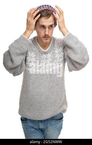 Junger, hübscher, großer, schlanker weißer Mann mit braunem Haar und Händen am Kopf in grauem Pullover, isoliert auf weißem Hintergrund Stockfoto