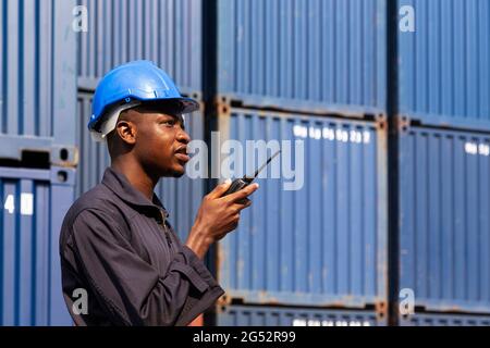 Schwarzer afrikanischer Amarikan Mann Arbeiter arbeiten Kontrolle Verladung Frachtcontainer an kommerziellen Schiffahrtsdock. Fracht Fracht Dock und Import Export logisti Stockfoto