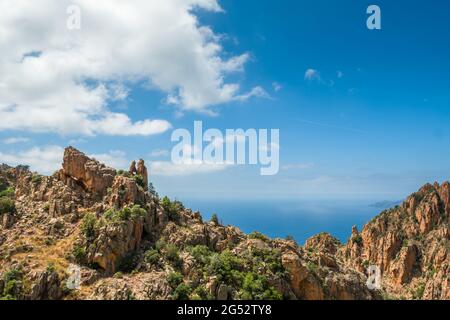 Dramatische Felsformationen mit einem herzförmigen Loch an den Calanques de Piana an der Westküste Korsikas mit Mittelmeer in der Ferne Stockfoto