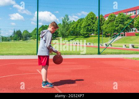 Junge Vorbereitung für Basketball-Schießen auf Playground.Boy führt Schuss bei Basketball-Spiel auf dem Spielplatz während sonnigen Sommertag. Stockfoto