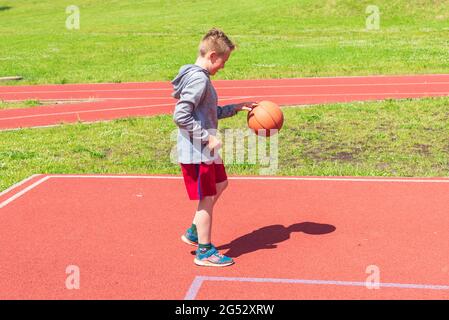 Junge Vorbereitung für Basketball-Schießen auf Playground.Boy führt Schuss bei Basketball-Spiel auf dem Spielplatz während sonnigen Sommertag. Stockfoto