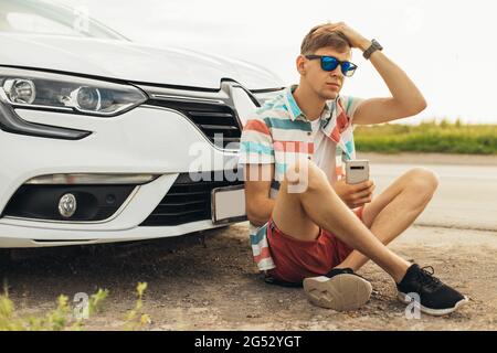 Reisen - junger, gutaussehender, glücklicher Mann mit Sonnenbrille, reist mit dem Auto, mietet im Urlaub ein Auto, Reisekonzept Stockfoto