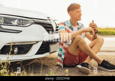 Reisen - junger, gutaussehender, glücklicher Mann mit Sonnenbrille, reist mit dem Auto, mietet im Urlaub ein Auto, Reisekonzept Stockfoto