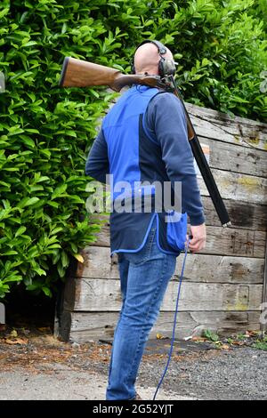 Mann hält Tontaube Auslöseschalter mit 12 Gauge Schusswaffe sicher auf seiner Schulter ruhen Stockfoto