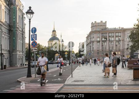 Moskau, Russland - am 21. Juni 2021 FÄHRT EIN Mann auf einem Elektroroller entlang der Straße Bolshaya Nikitskaya auf einem Radweg Stockfoto