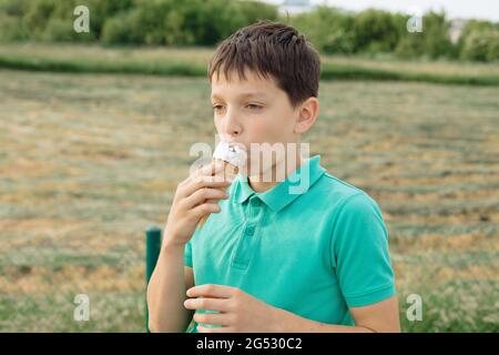 Junge 11 Jahre alt, der ein Eis isst. Teenager Junge im Urlaub, Sommer, Schweißmoment Stockfoto