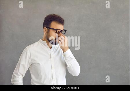 Müde junge Geschäftsmann reiben seine angespannten Augen nach einem langen stressigen Arbeitstag Stockfoto