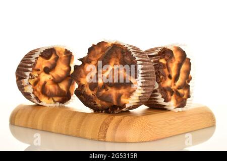 Drei duftende Schokoladenkuckuffins auf einem runden Holztablett, Nahaufnahme, auf weißem Hintergrund. Stockfoto