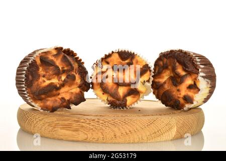 Drei duftende Schokoladenkuckuffins auf einem runden Holztablett, Nahaufnahme, auf weißem Hintergrund. Stockfoto