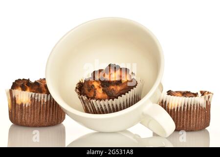 Drei duftende Schokoladenkuckuffins mit einer weißen Tasse, Nahaufnahme, auf weißem Hintergrund. Stockfoto