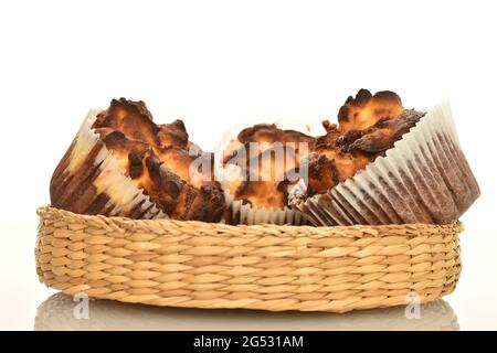 Drei duftende Schokoladenkuhmuffins in einem Strohteller, Nahaufnahme, isoliert auf Weiß. Stockfoto