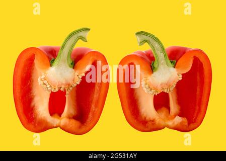 Rote Paprika in zwei Hälften geschnitten im Querschnitt, isoliert auf gelb Stockfoto