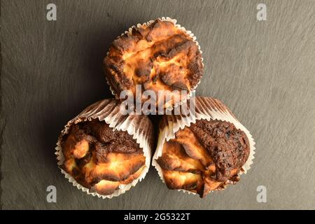 Drei duftende Schokoladenkuckuffins auf einem Schieferbrett, Nahaufnahme, Draufsicht. Stockfoto