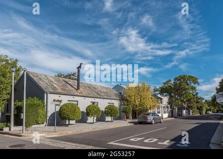 FRANSCHHOEK, SÜDAFRIKA - 12. APRIL 2021: Eine Straßenszene mit Geschäften und Fahrzeugen in Franschhoek in der Provinz Westkap Stockfoto