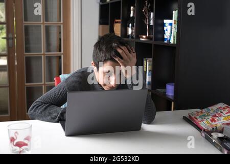 Müde britische Schuljunge, 13-14 Jahre alt, mit Online-Unterricht während der Covid-19 Pandemie, Surrey, Großbritannien Stockfoto