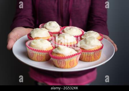 Teller mit hausgemachten, zuckerglasierten Cupcakes, UK Stockfoto