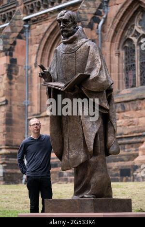 Der Bildhauer Peter Walker mit seiner Bronzestatue des Heiligen Tschad, des ersten Bischofs von Lichfield und des Gründers der Lichfield Cathedral, schließt seine Reise von einer Gießerei in Wales zur Kathedrale Close in der Lichfield Cathedral, Staffordshire. Bilddatum: Freitag, 25. Juni 2021. Stockfoto