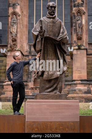 Der Bildhauer Peter Walker mit seiner Bronzestatue des Heiligen Tschad, des ersten Bischofs von Lichfield und des Gründers der Lichfield Cathedral, schließt seine Reise von einer Gießerei in Wales zur Kathedrale Close in der Lichfield Cathedral, Staffordshire. Bilddatum: Freitag, 25. Juni 2021. Stockfoto